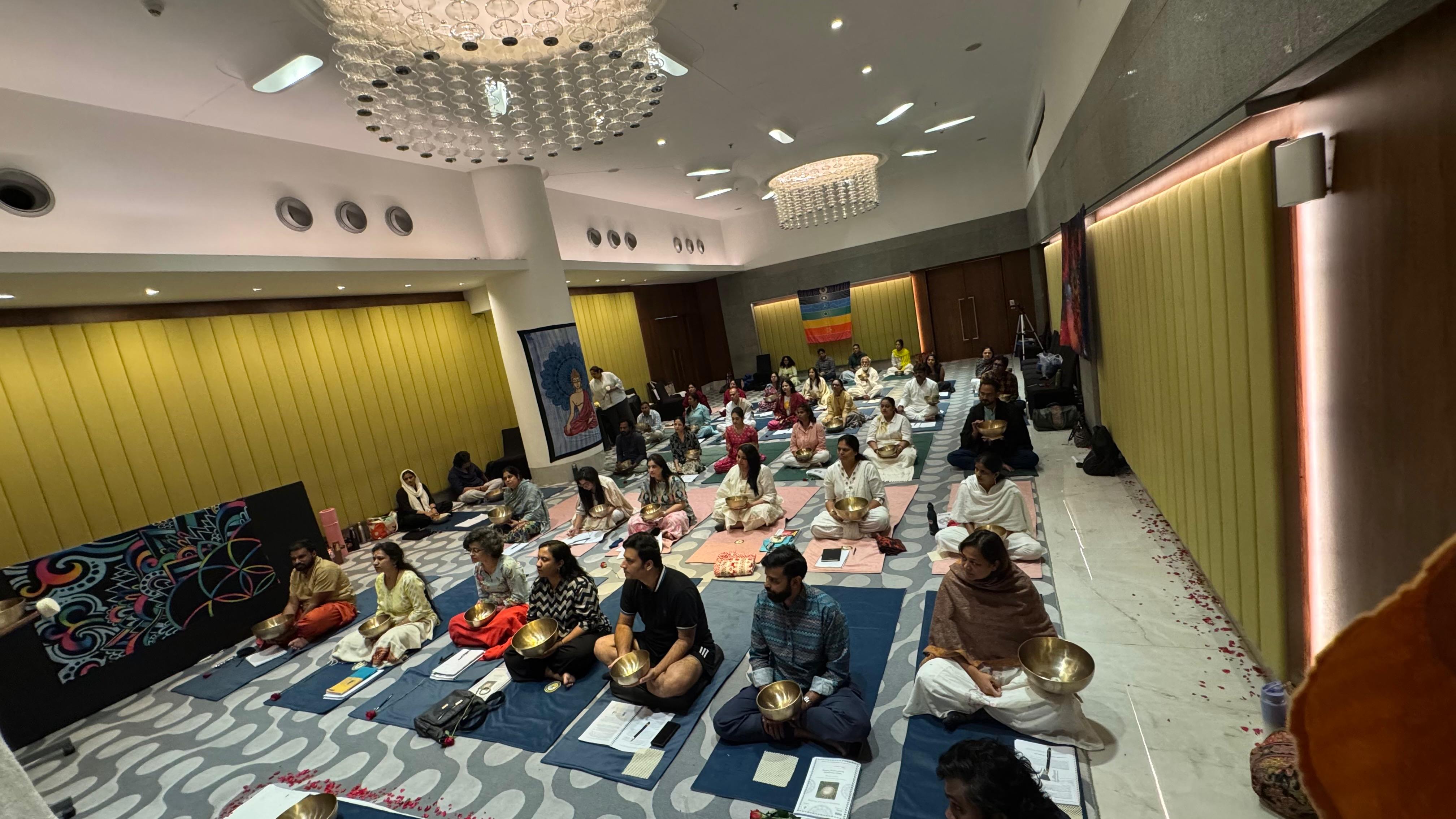 Large group sound bath session — participants seated with singing bowls